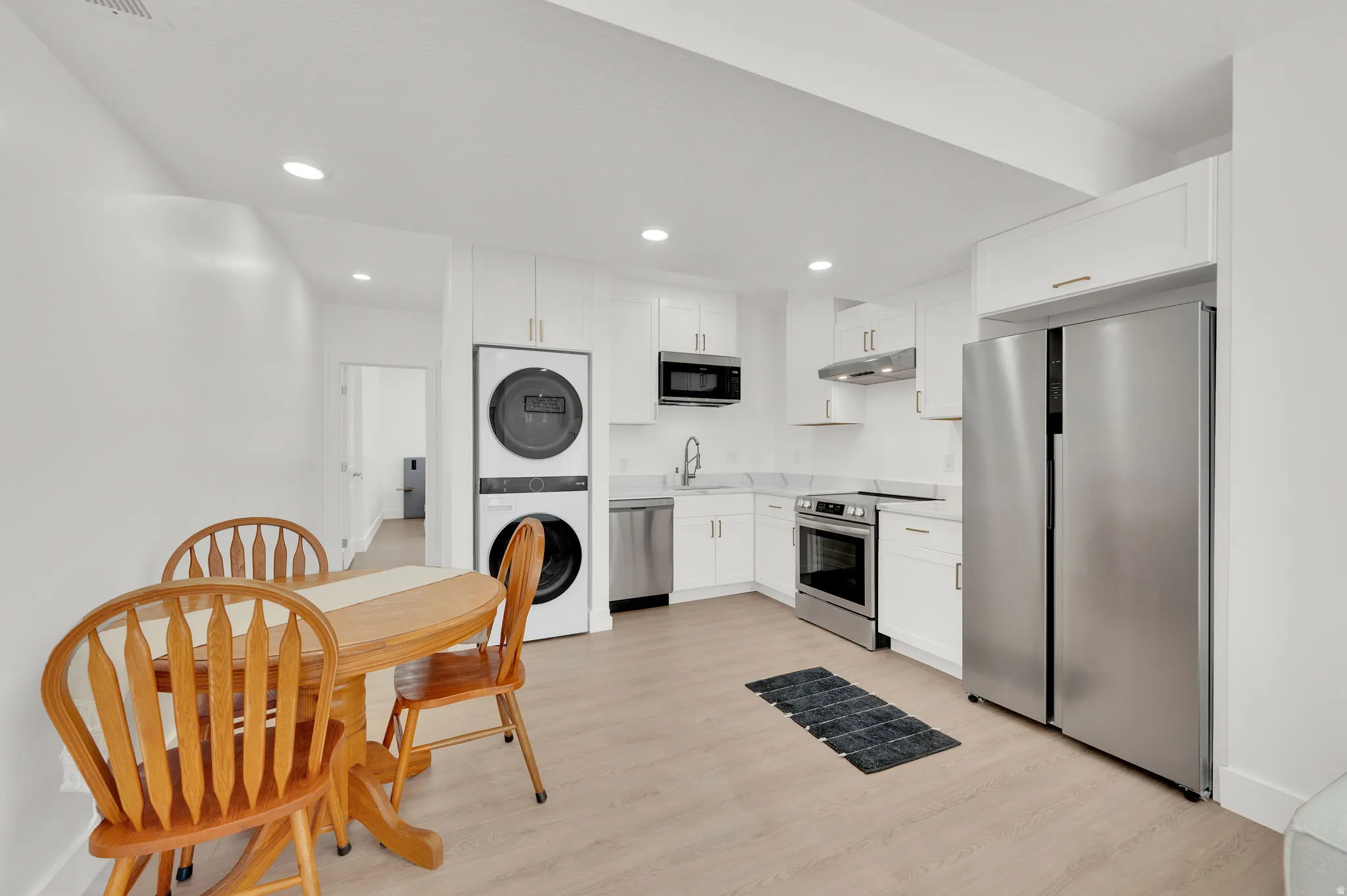Kitchen featuring stainless steel appliances, light countertops, white cabinets, recessed lighting, and light wood-style flooring