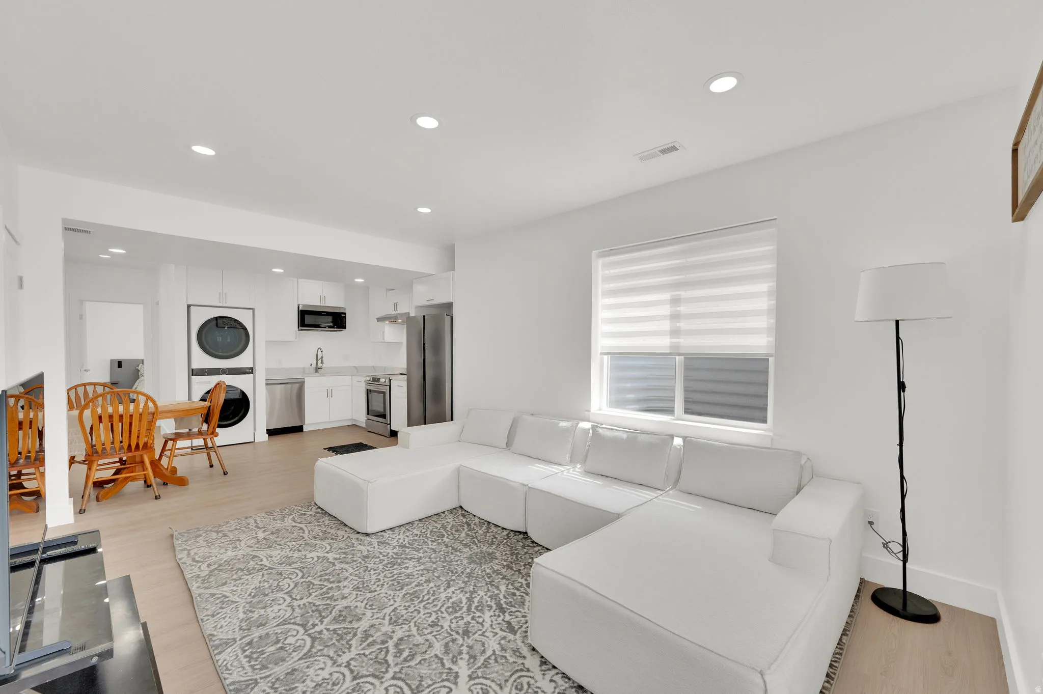 Living area featuring recessed lighting, light wood-type flooring, and stacked washer / dryer