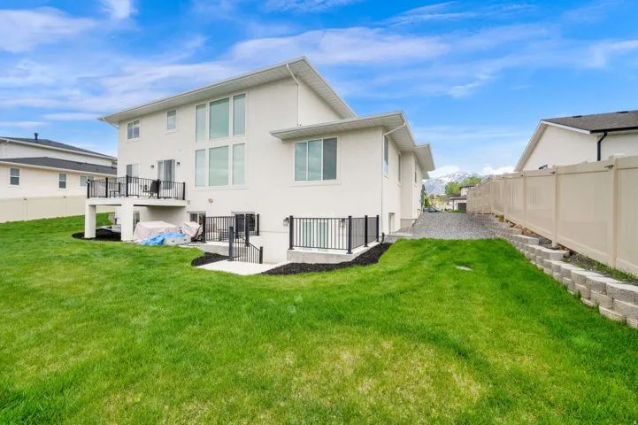 Rear view of house with stucco siding, a fenced backyard, and a patio area