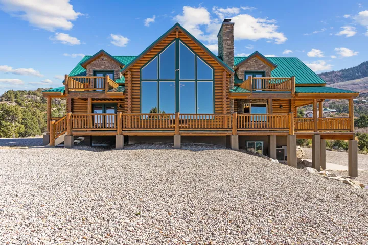 Rear view of property featuring log exterior, a deck, a chimney, and a metal roof