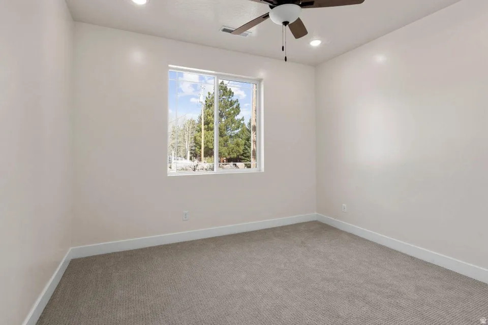 Empty room with light carpet, ceiling fan, and recessed lighting
