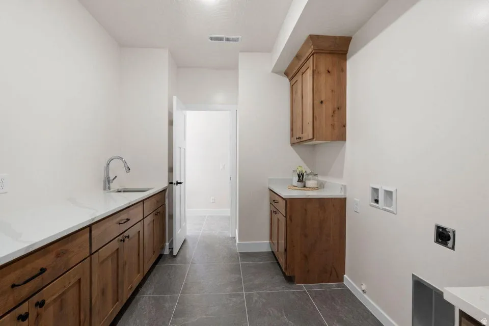 Laundry room featuring washer hookup, cabinet space, hookup for an electric dryer, and dark tile patterned flooring