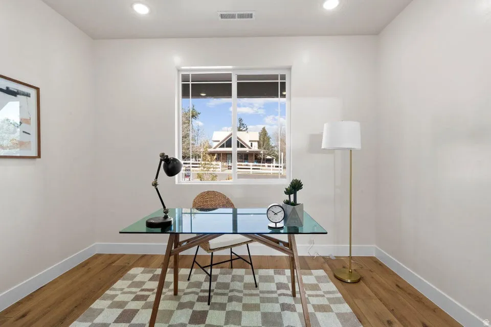Home office with light wood-style floors and recessed lighting