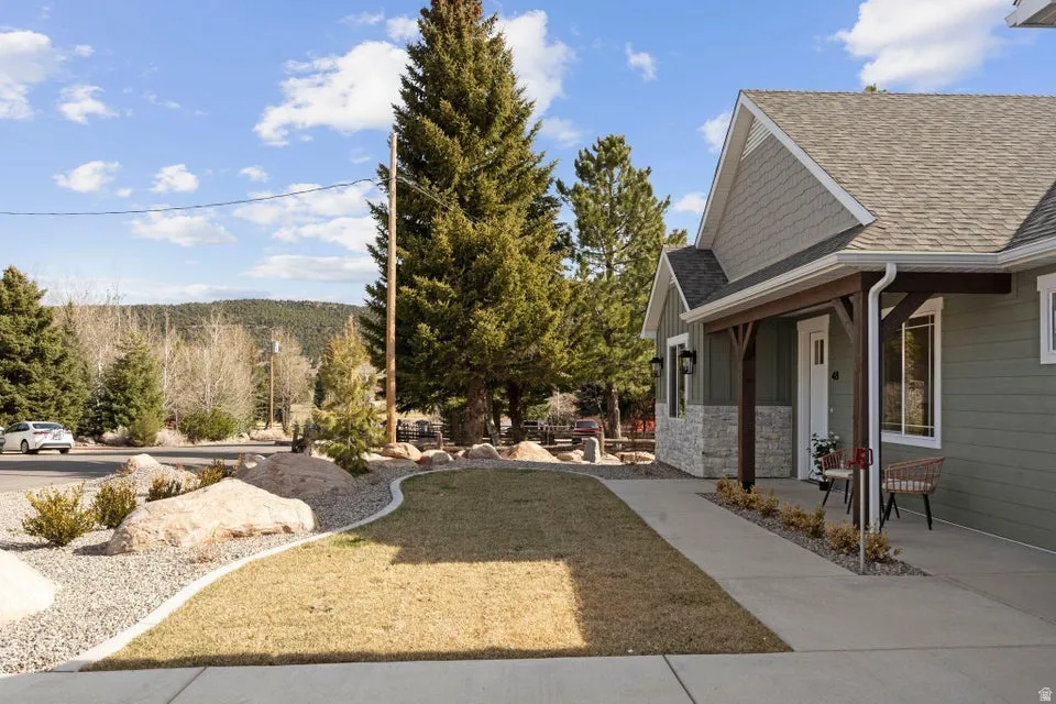 View of grassy yard with covered porch
