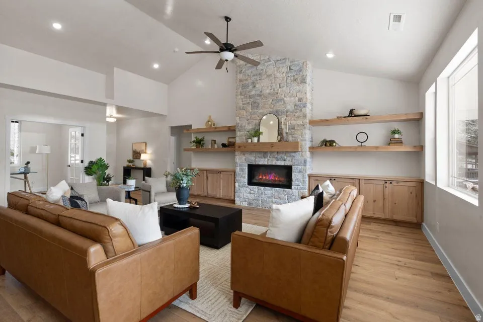 Living area featuring ceiling fan, healthy amount of natural light, light wood-type flooring, and vaulted ceiling