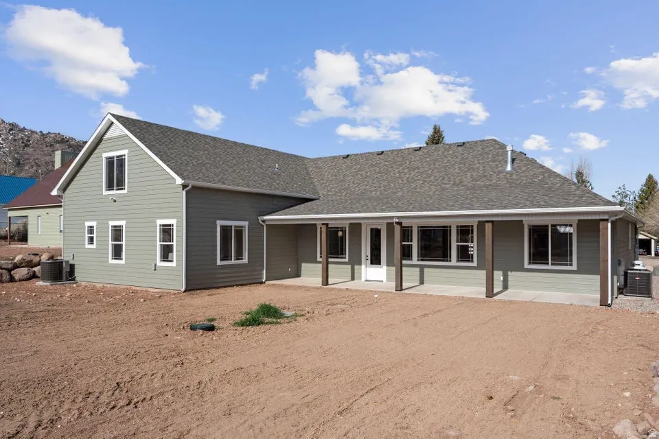 Back of house featuring roof with shingles and a patio
