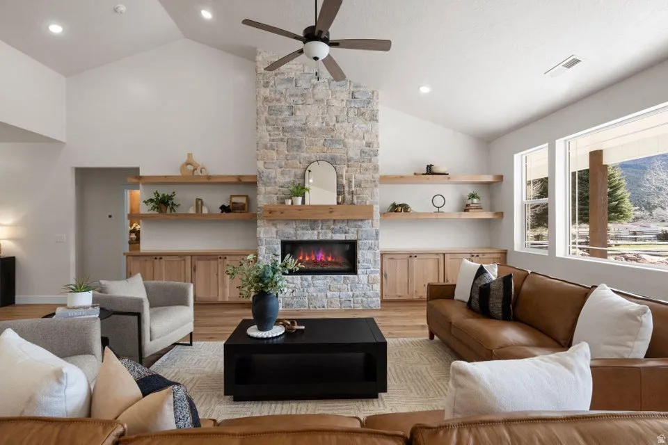 Living room with light wood-style flooring, ceiling fan, a fireplace, vaulted ceiling, and recessed lighting