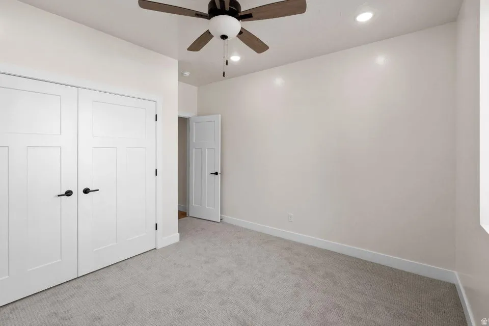 Unfurnished bedroom with light colored carpet, a closet, ceiling fan, and recessed lighting