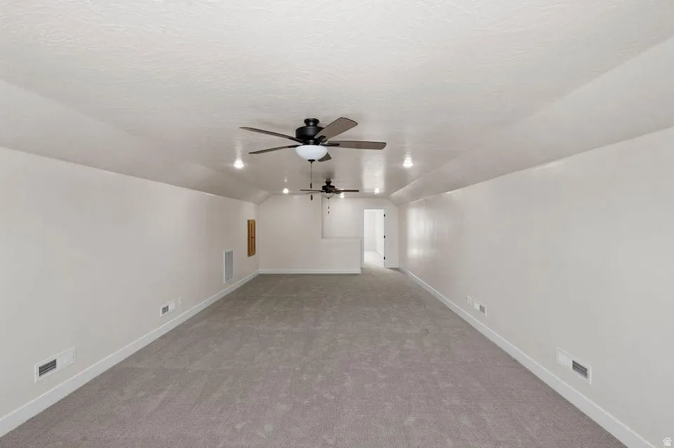 Spare room featuring a ceiling fan and light colored carpet