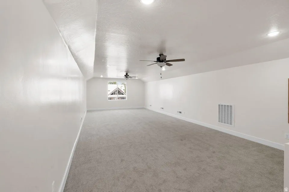 Bonus room with carpet floors and ceiling fan