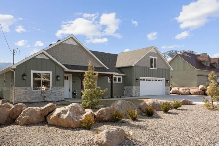 Craftsman inspired home featuring board and batten siding, stone siding, covered porch, concrete driveway, and a shingled roof