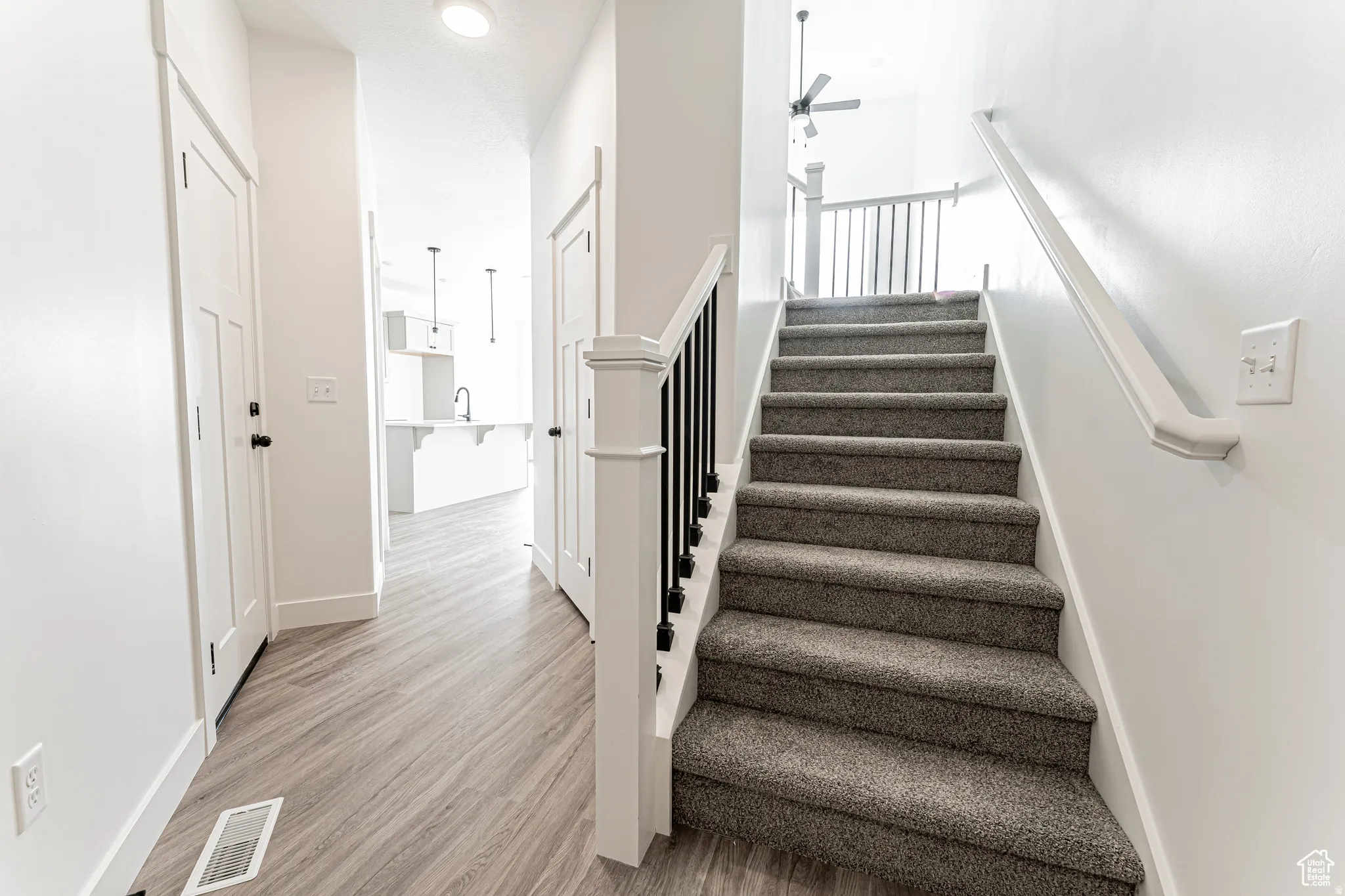 Stairs featuring ceiling fan and wood finished floors