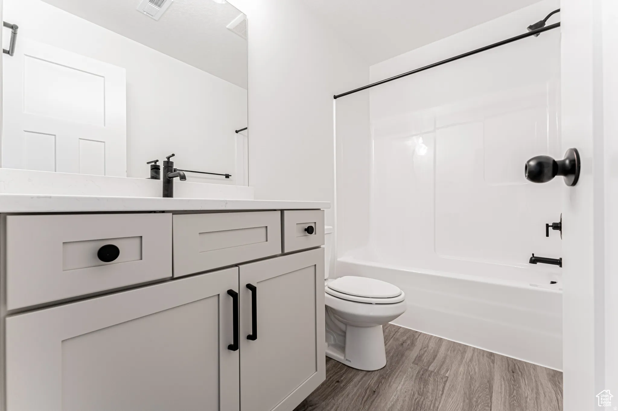 Bathroom with vanity, dark wood-style floors, and bathtub / shower combination