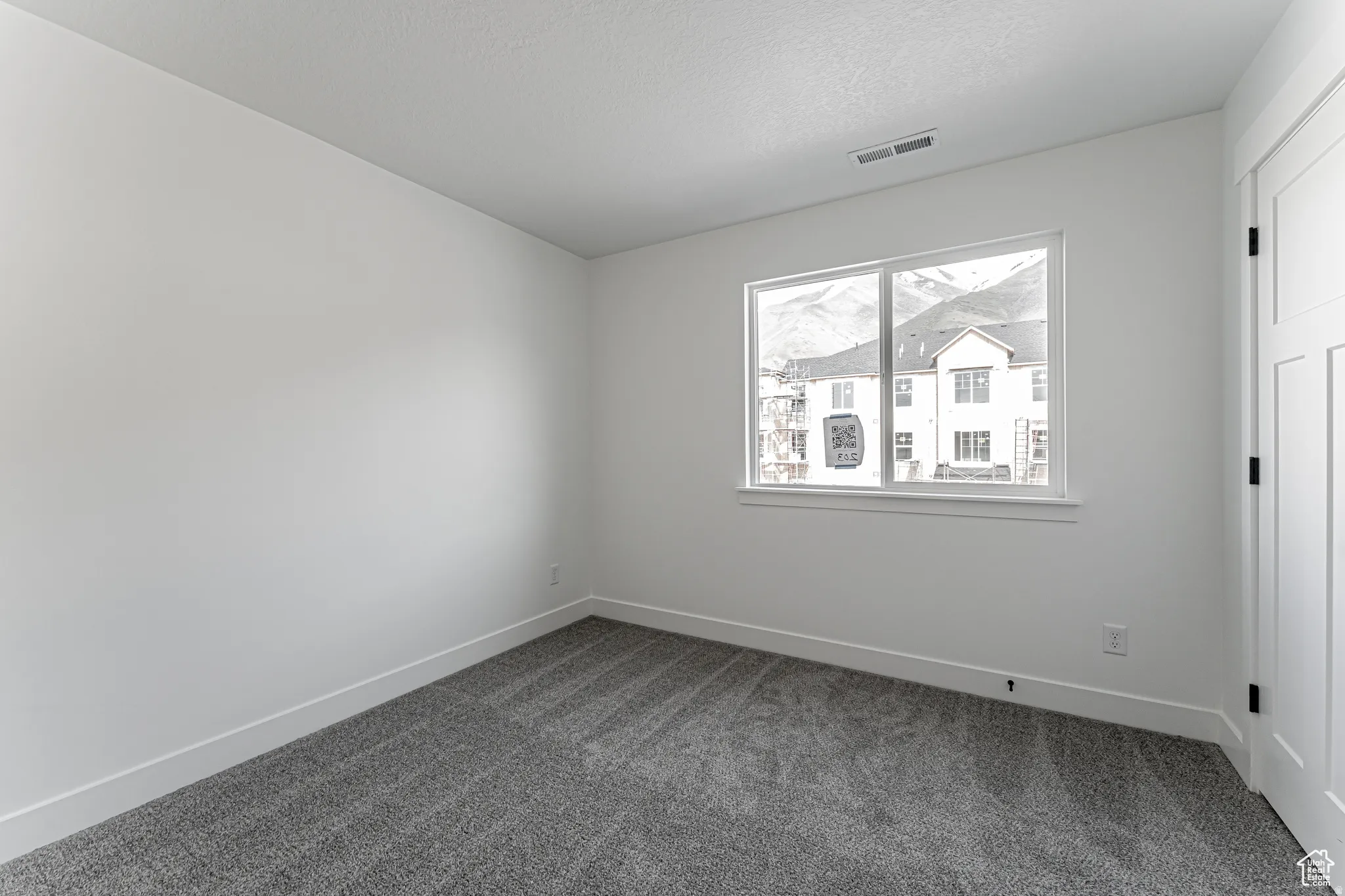 Empty room with dark carpet and a textured ceiling