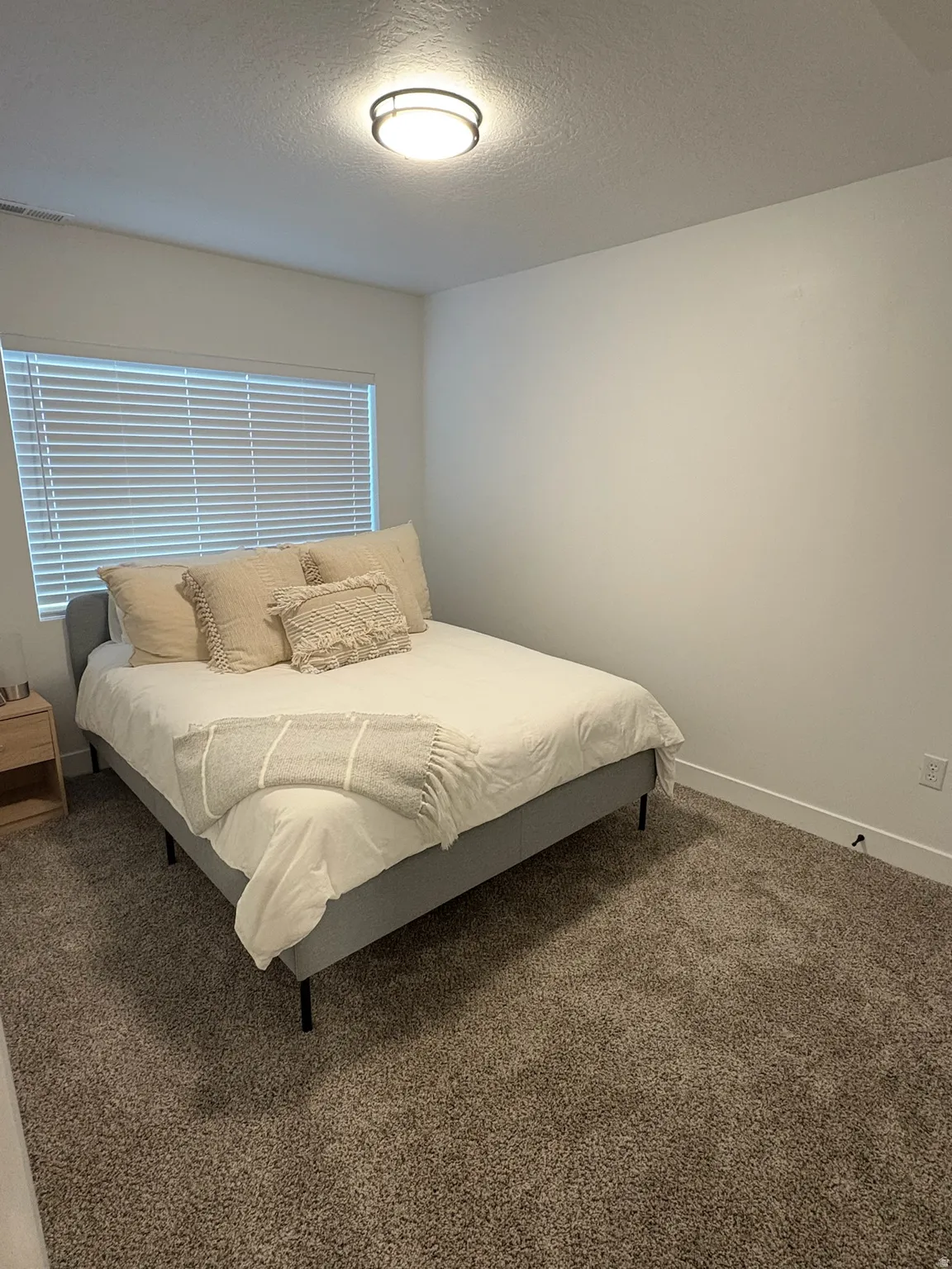 Bedroom with dark carpet and a textured ceiling