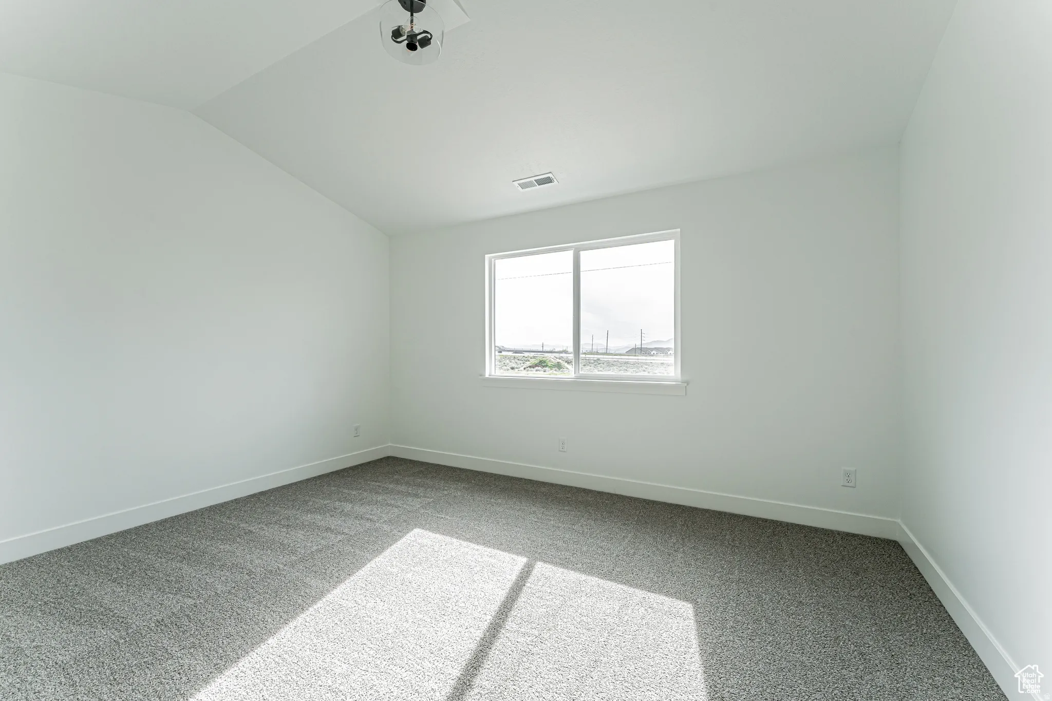 Spare room featuring light colored carpet and lofted ceiling