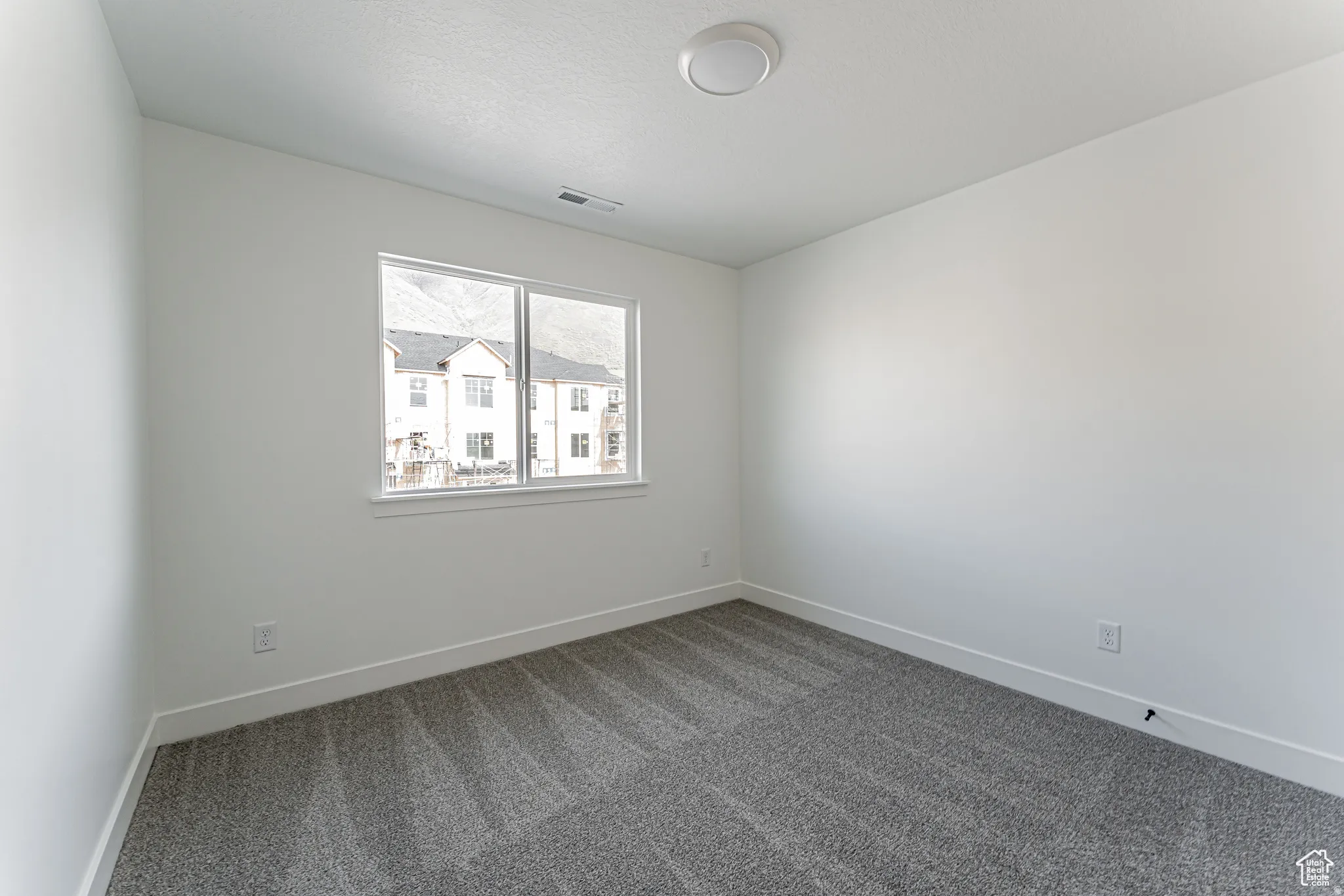 Unfurnished room with baseboards and dark carpet