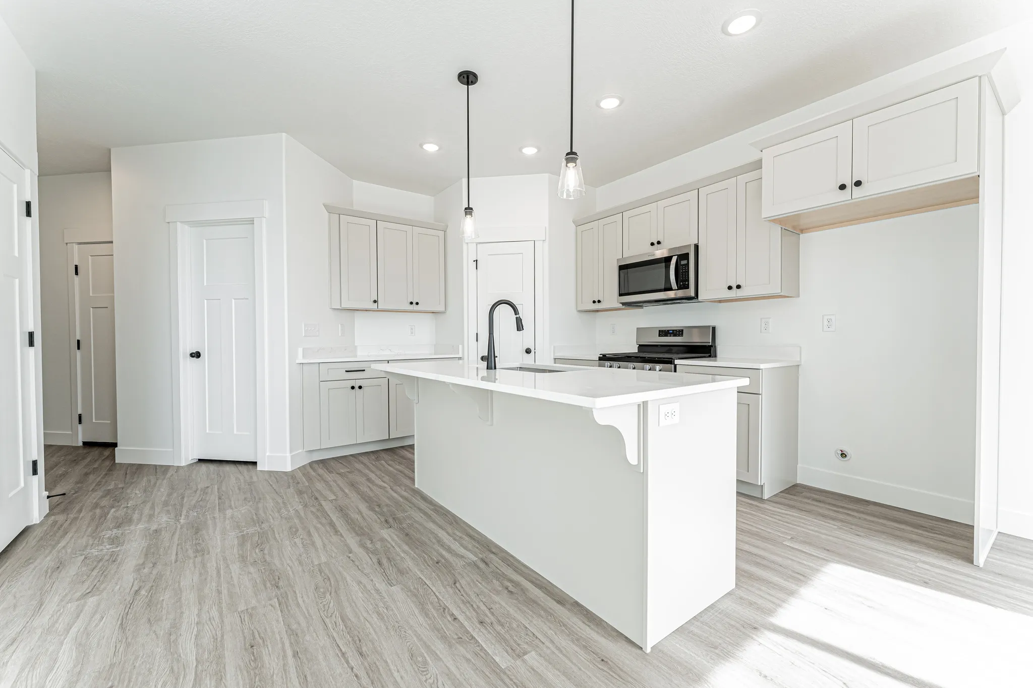 Kitchen featuring a breakfast bar, stainless steel appliances, light wood-style flooring, pendant lighting, and a center island with sink