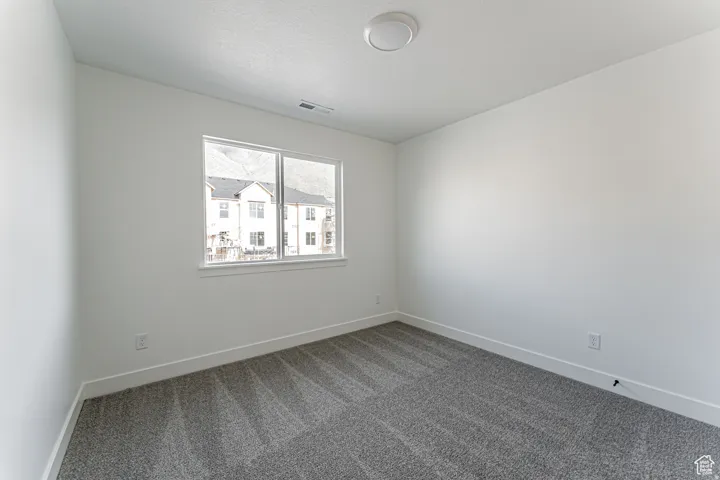 Unfurnished room with baseboards and dark carpet