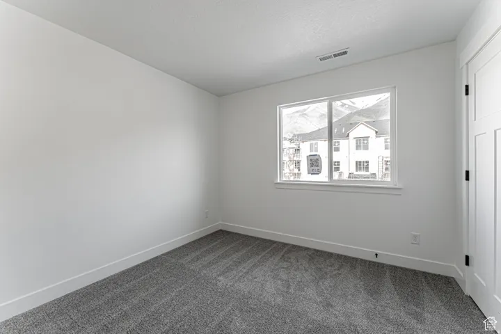 Empty room with dark carpet and a textured ceiling