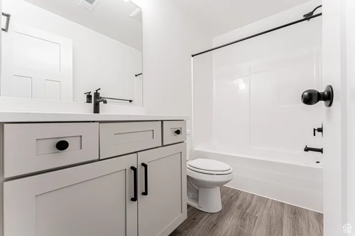 Bathroom with vanity, dark wood-style floors, and bathtub / shower combination