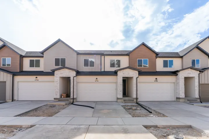 View of front of home featuring stone siding, concrete driveway, and a garage