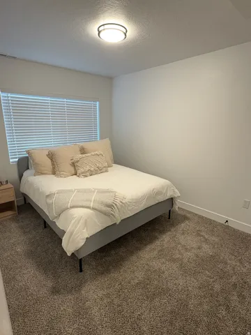 Bedroom with dark carpet and a textured ceiling