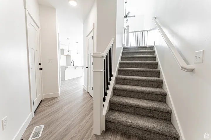 Stairs featuring ceiling fan and wood finished floors