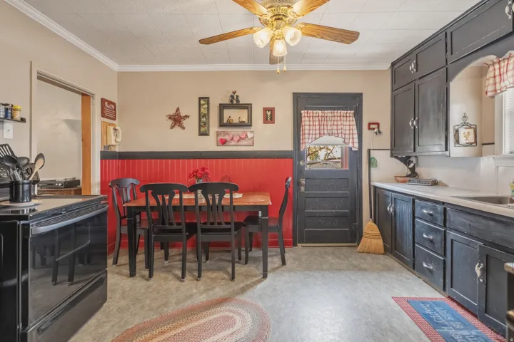 Dining area featuring a ceiling fan, crown molding, and wainscoting