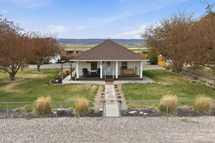 View of front of home featuring a gate, a porch, a fenced front yard, and a shingled roof
