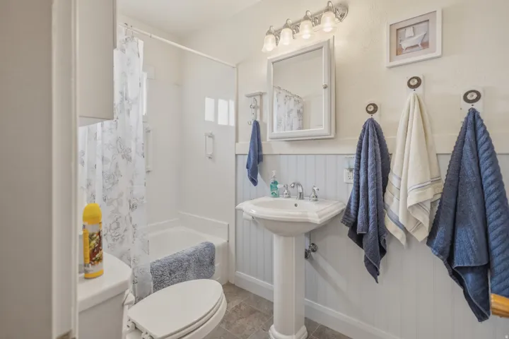 Bathroom featuring shower / bathtub combination with curtain and wainscoting