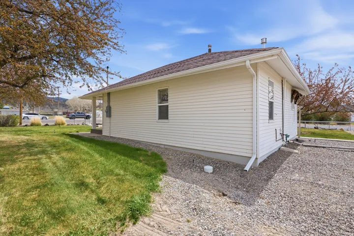 View of side of property featuring a yard and roof with shingles