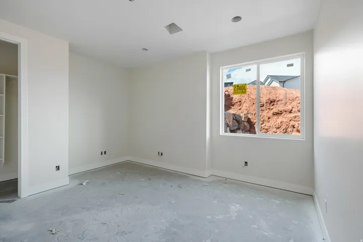 Unfinished interior room featuring light-toned walls, a white trim baseboard, and a double-pane window