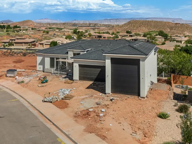 Contemporary single-story residence with a multi-car garage, featuring dark tile roofing and light-toned stucco exterior