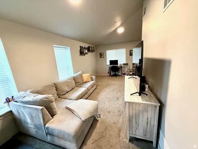 Living area with lofted ceiling, an office area, and carpet floors