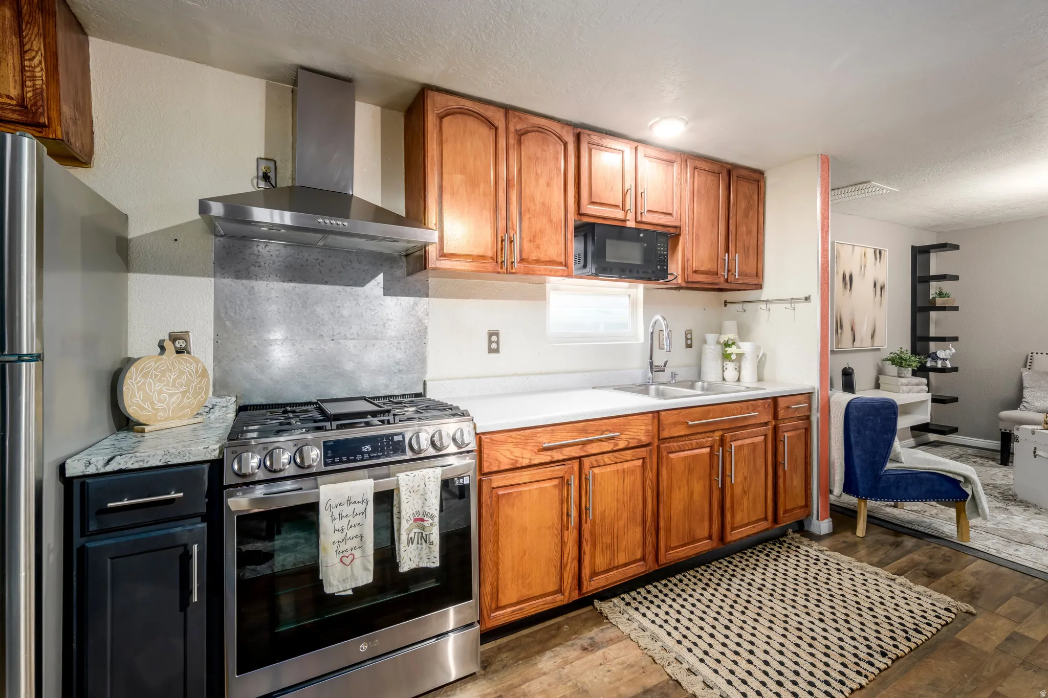Kitchen with stainless steel appliances, light countertops, wood finish cabinetry, light wood finished floors, and a textured ceiling