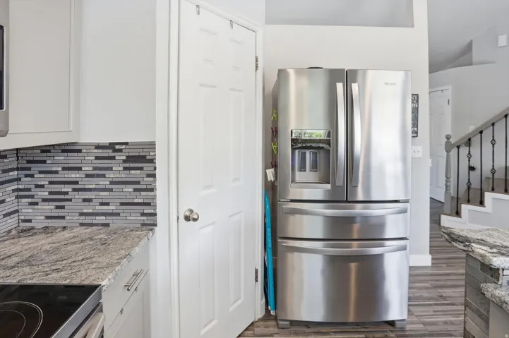 Kitchen with stainless steel fridge, light stone countertops, white cabinetry, electric range, and dark wood finished floors
