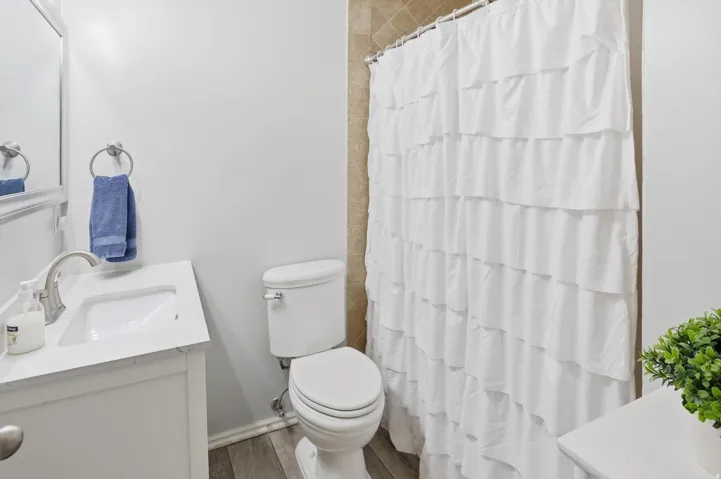 Bathroom featuring vanity, a shower with curtain, and dark wood-style flooring