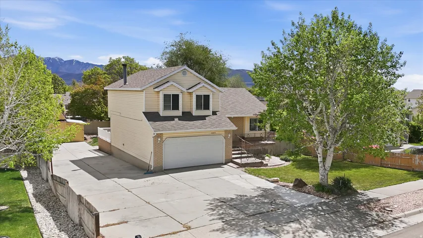 Traditional-style house with a shingled roof, a garage, concrete driveway, a mountain view, and brick siding