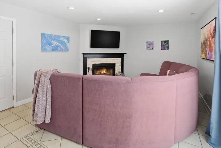 Living room with light tile patterned floors, recessed lighting, and a fireplace