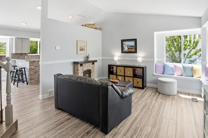 Living area with a fireplace, light wood-style flooring, and vaulted ceiling