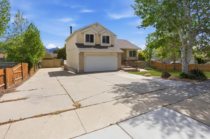 Traditional-style home featuring concrete driveway, brick siding, a shingled roof, and an attached garage