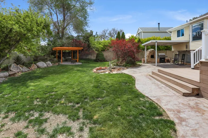 Fenced backyard featuring a fire pit, a patio area, and a wooden deck