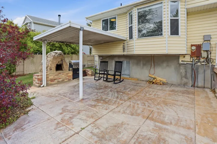 View of patio with an outdoor fireplace and area for grilling