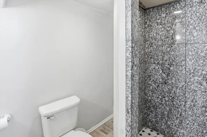 Full bath with a stall shower and light wood-style flooring