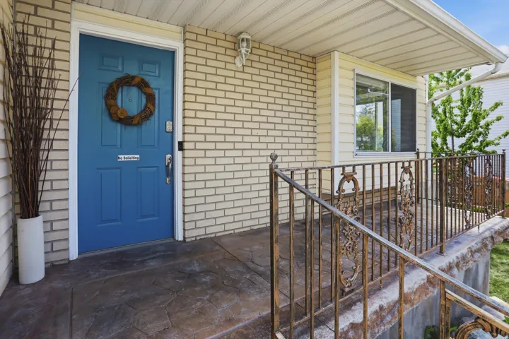View of exterior entry with brick siding and covered porch