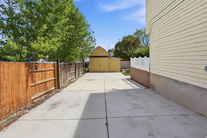 Fenced backyard featuring a storage unit