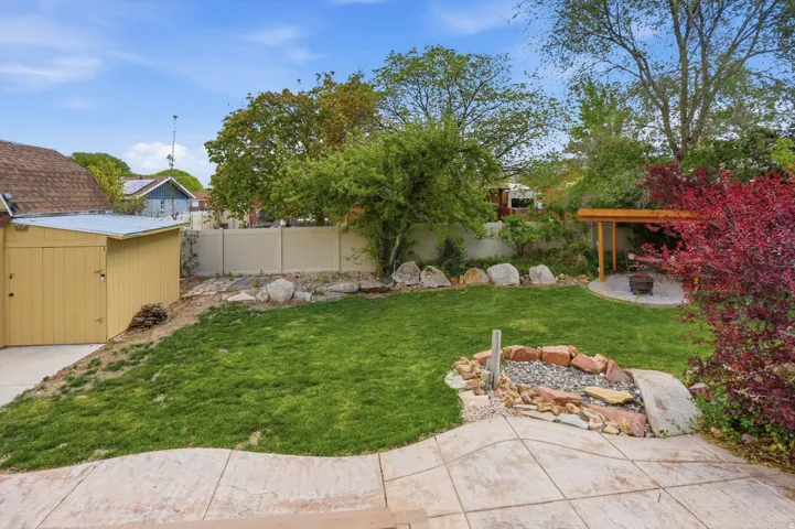 Fenced backyard featuring an outdoor fire pit, a storage unit, and a patio