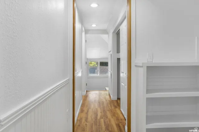Hall with light wood-type flooring, recessed lighting, and a textured wall