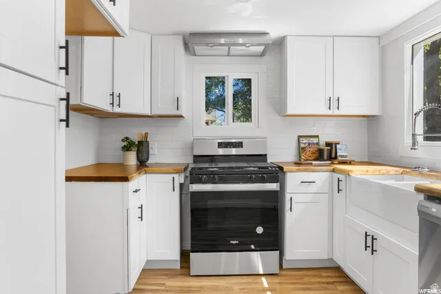 Kitchen featuring wooden counters, stainless steel appliances, white cabinets, light wood-type flooring, and plenty of natural light